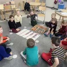 Dzieci na rocznym przygotowaniu przedszkolnym uczą się liter z pudełka z literami.