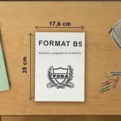 Porównanie rozmiarów: zeszyt A5 obok notatnika B5. Na biurku leżą też przybory szkolne.