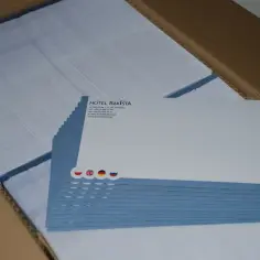 Stos białych kopert z niebieskim paskiem i logo hotelu. W tle kolejne koperty w kartonie.