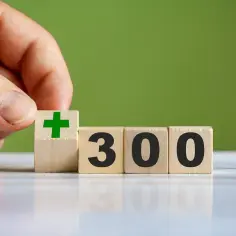 Ręka dodaje kostkę z zielonym plusem do kostek z napisem "300". Od kiedy 300 plus, wszystko idzie w dobrym kierunku.