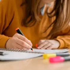 Uczennica 4 klasy liceum podkreśla notatki. W tle kolorowe zakreślacze, które symbolizują przedmioty odchodzące w zapomnienie.
