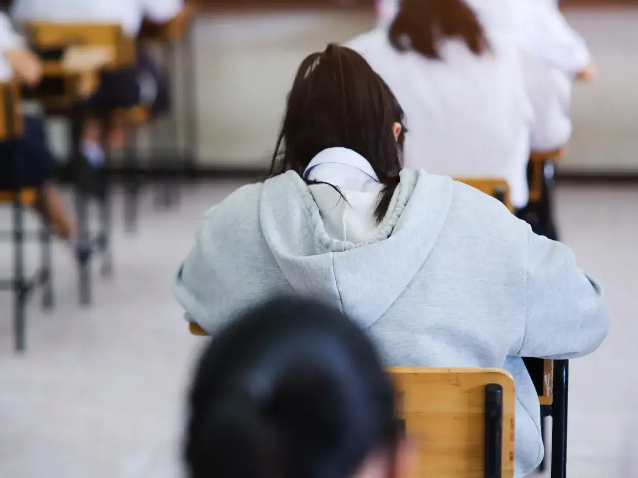 Uczniowie siedzą w klasie, czekając na wyniki matur. Szkoła w chmurze to metafora przyszłości edukacji.