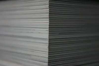 Stos kartek papieru tworzy geometryczny wzór. Każda linia to kolejny arkusz, tworzący wrażenie głębi i porządku.